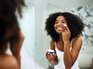 woman moisturizing her face in the bathroom mirror to relieve itching